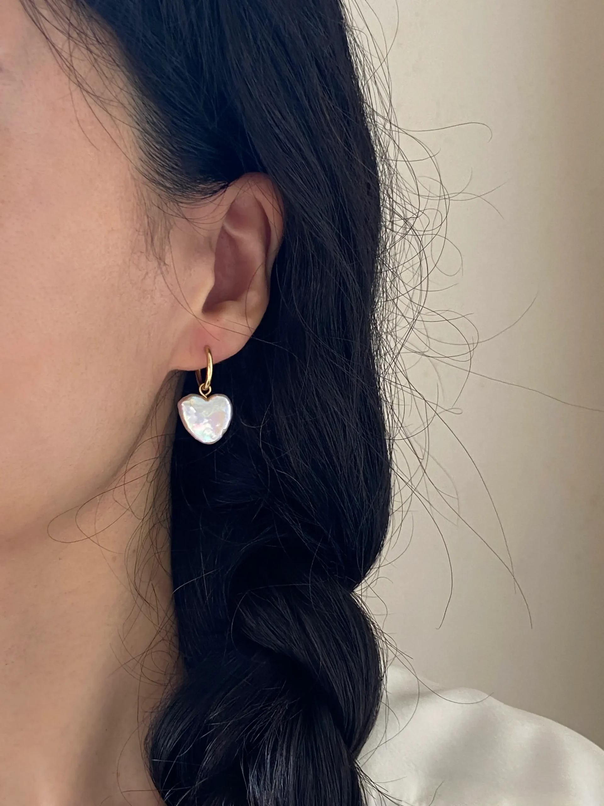 Natural heart-shaped pearl hoop earrings worn on ear