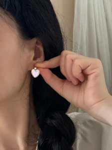 Natural heart-shaped pearl stud earrings with zircon worn on ear