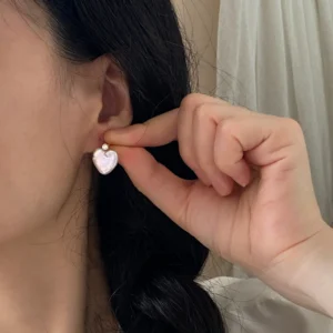 Natural heart-shaped pearl stud earrings with zircon worn on ear